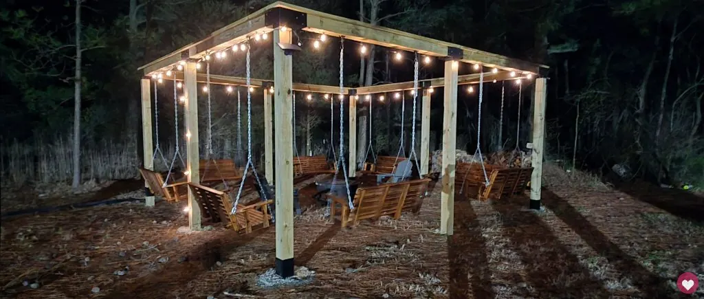 Couple on the pergola swing chairs at evening under string lights