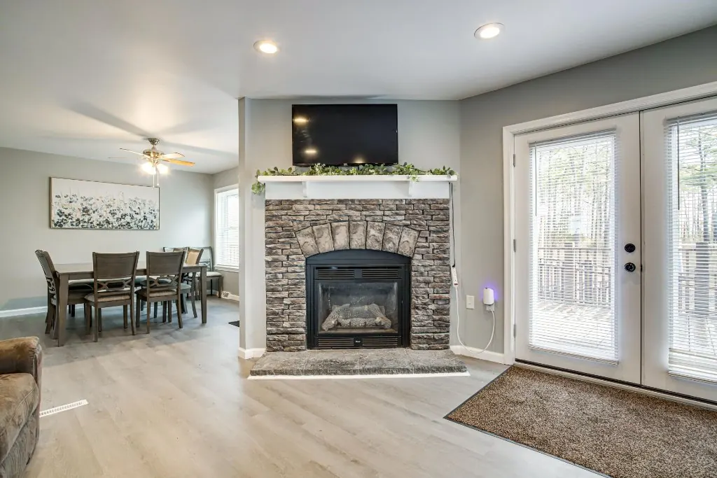 The living room's stone fireplace, with French doors and the dining room beyond